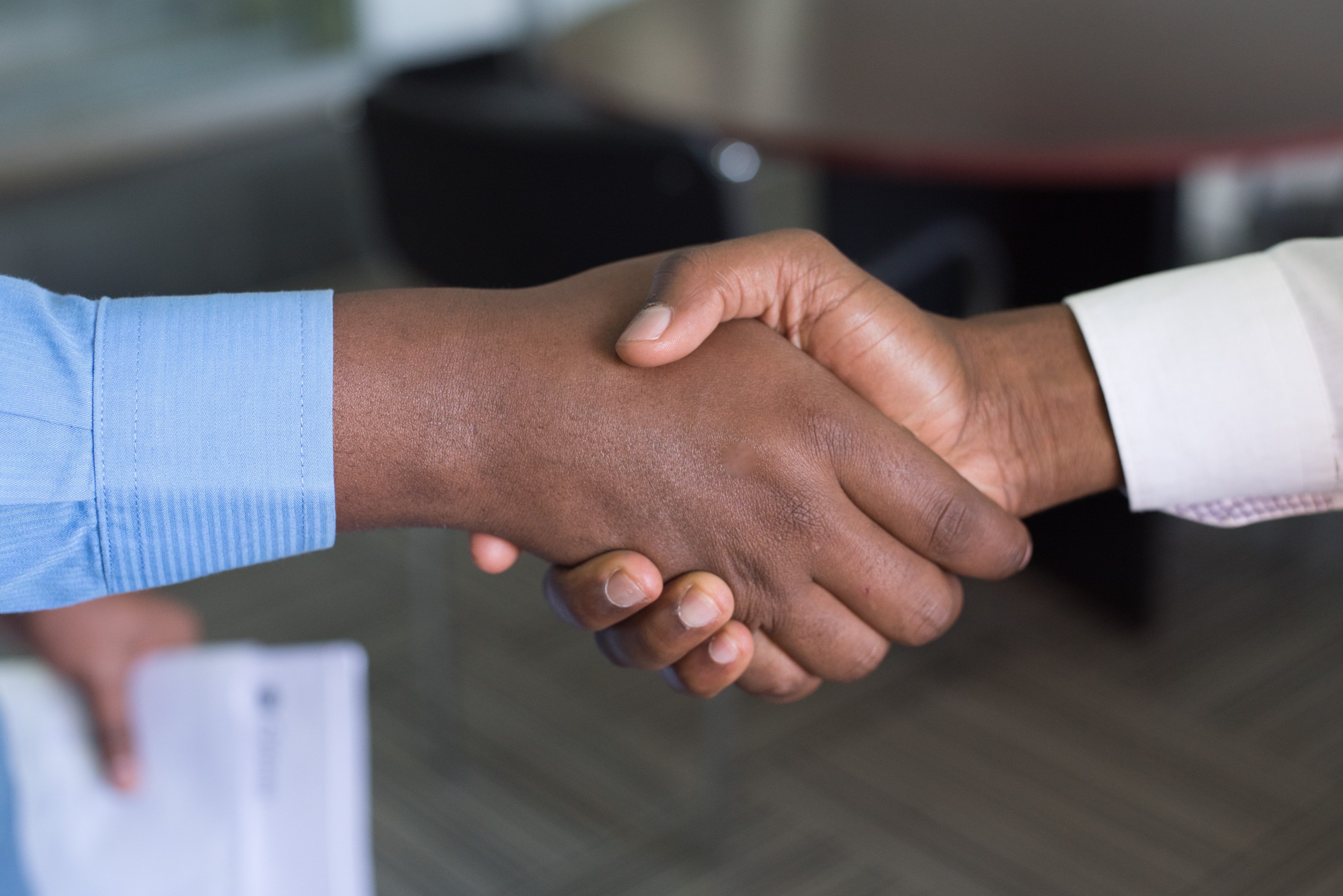 Closeup of handshake among formally dressed African-American men in office setting